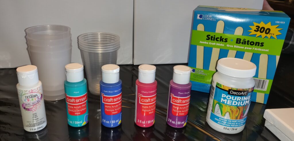 Our starting supplies--acrylic paint, pouring medium, canvases, plastic cups, craft sticks
